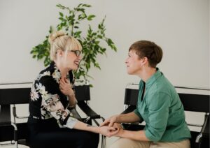Coach and client are holding hands in a powerful moment of empathy and connection during their coaching conversation, demonstrating deep trust and safety in the coaching relationship