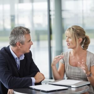 Coach actively listening to the client as they confidently design an action plan, following the client's newfound awareness during their face-to-face coaching session